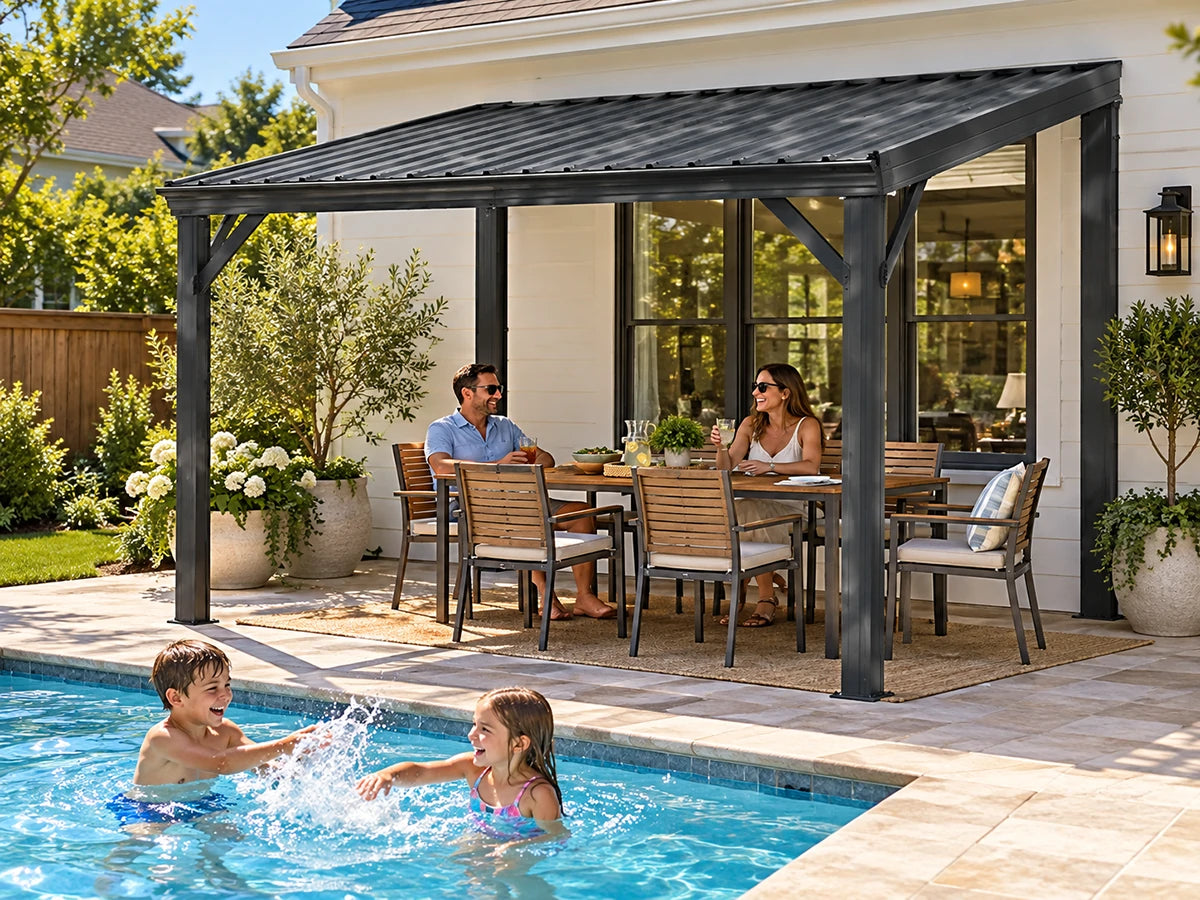 A large black metal patio gazebo with a slatted roof sits beside a swimming pool, with a man and woman sitting underneath on a dining set. Two children splash in the pool in the foreground.